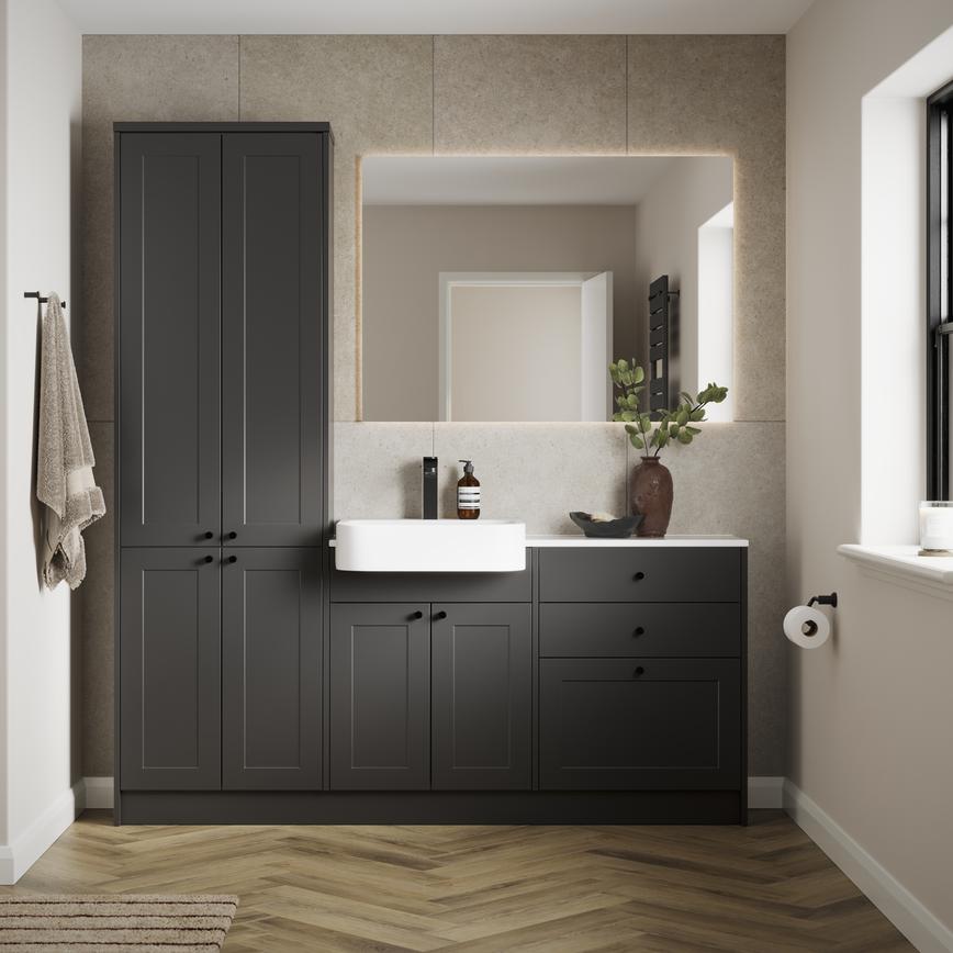 A single-wall, shaker bathroom in a charcoal tone. It has herringbone flooring, white worktops, and a ceramic sink.