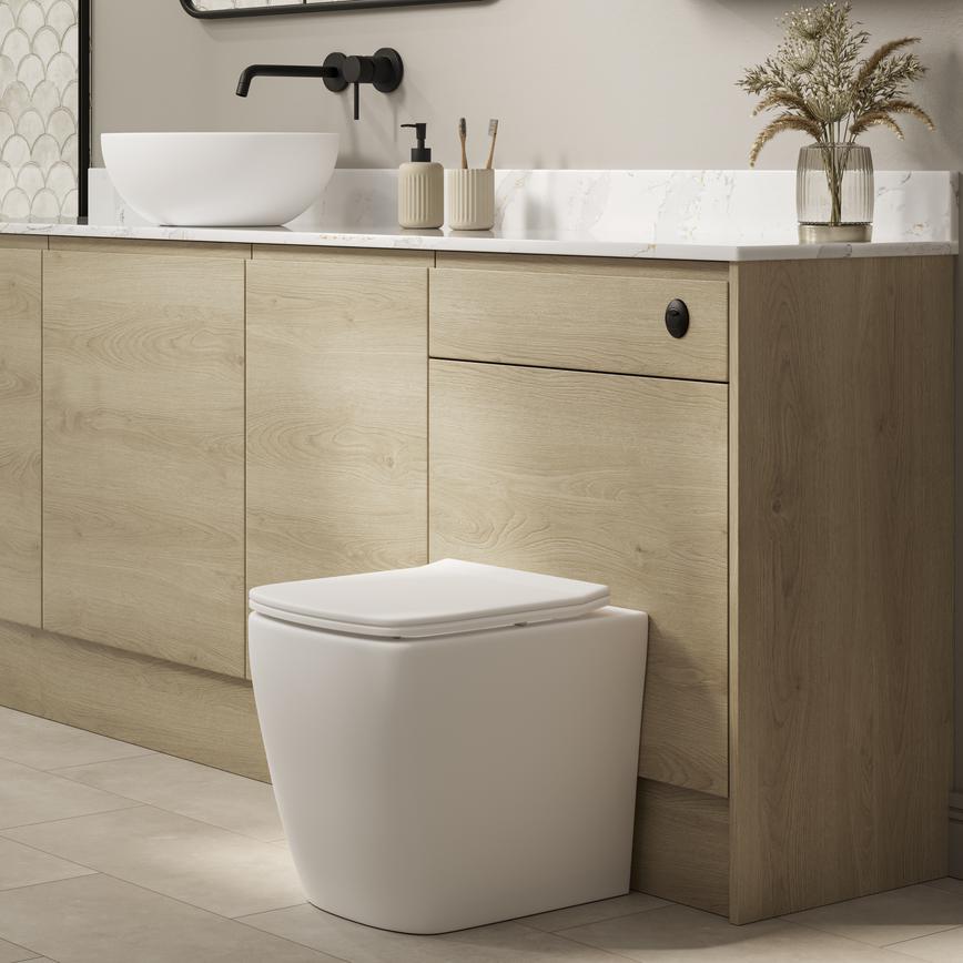A Clerkenwell natural oak bathroom, with shower. It has a matching cistern cabinet, black accessories, & marble countertop.