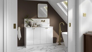 A small white bathroom with gloss cabinets and brass fittings. There is marble wall panelling and matching floors throughout